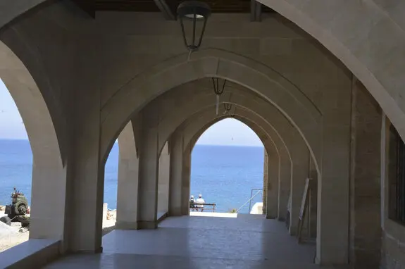Steinbogengang im Kloster Apostolos Andreas auf Zypern mit Blick auf das Mittelmeer – Symbol für Stabilität und Vermögensschutz.